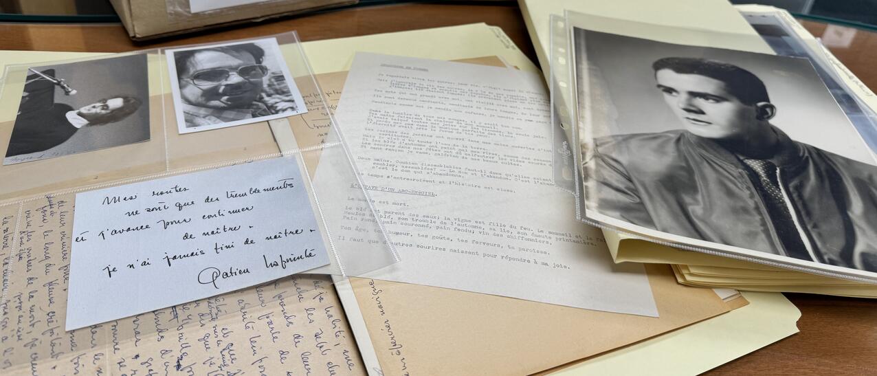 Archives sorties d'un carton sur un bureau avec des photos en noir et blanc, un mot manuscrit...