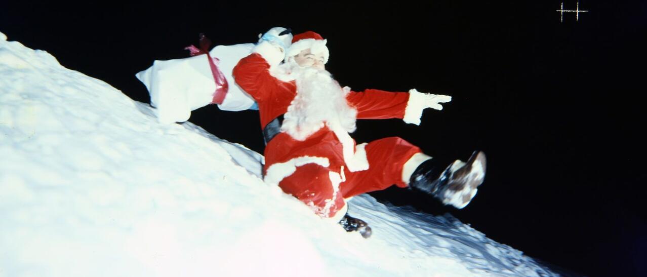 Un père Noël glisse sur la neige.