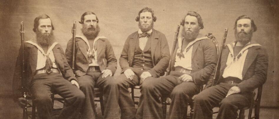 Photographie ancienne de cinq marins assis en uniforme.