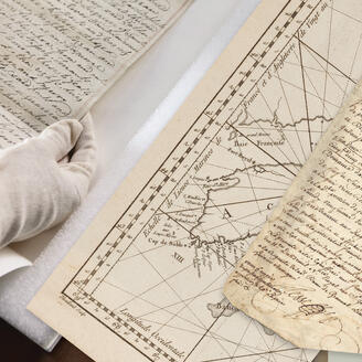 Vieux documents consultés par un employés des Archives nationales