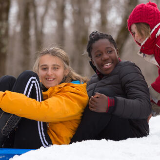 Des enfants sur une luge dans la neige.