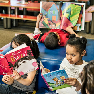 Enfants qui lisent des livres à l'Espace Jeunes de la Grande Bibliothèque.