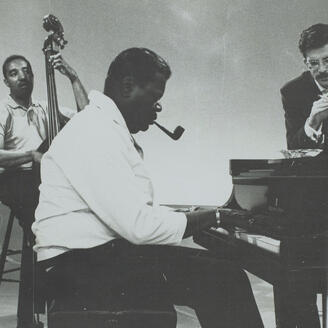 Un joueur de contrebasse et un pianiste à l'oeuvre, observés par un homme.