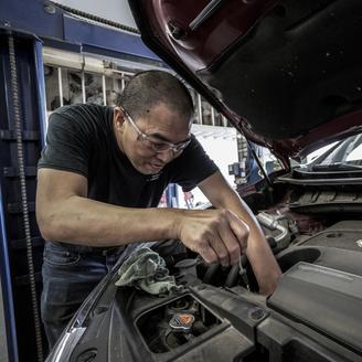 Un homme répare le moteur d'une voiture.