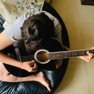 Jeune femme jouant de la guitare acoustique.