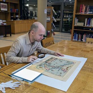 Photographie d’Alban Berson, examinant une carte géographique