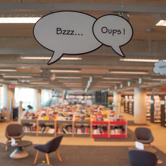 Phylactères contenant les onomatopées Bzzz et Oups suspendus au plafond de l'espace BD de la Grande Bibliothèque