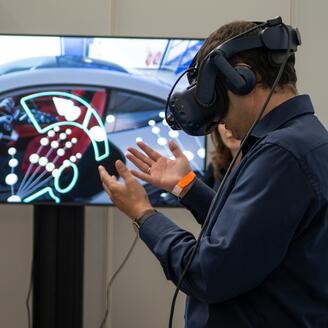 Homme portant une casque de réalité virtuelle devant un écran.