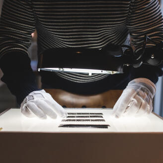 Un archiviste observe des négatifs sur une table lumineuse.