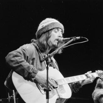 Serge Fiori chante et joue de la guitare tandis que Louis Valois, à ses côtés, le regarde. en concert