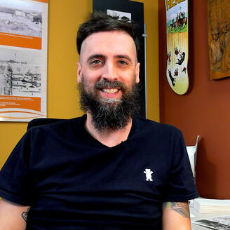 Portrait d'un homme barbu et souriant.