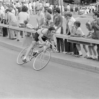 Coureur cycliste négociant un virage, devant une foule de spectateurs.