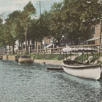 Vue du canal de Lachine, sur laquelle on aperçoit des canots accostés le long de quais. 