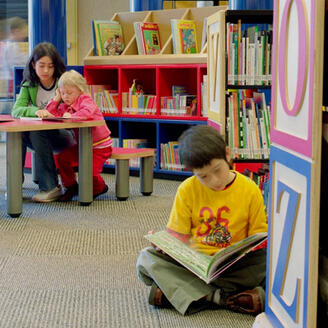 Photographie d'enfants consultant des livres à l'Espace Jeunes de la Grande Bibliothèque de Montréal