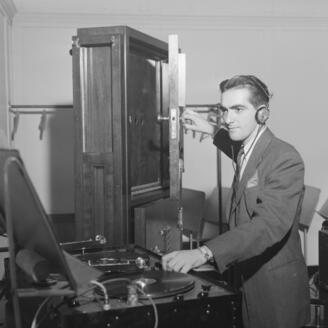 Une personne portant des écouteurs manipule de l’équipement audio et la porte d’une armoire, afin d’émettre un bruit.