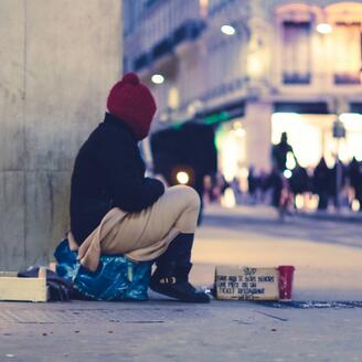 Personne sans-abri assis sur un trottoir. 