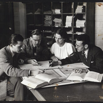 Quatre personnes regardent des plans et des livres d'étude. 