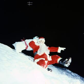 Un père Noël glisse sur la neige.