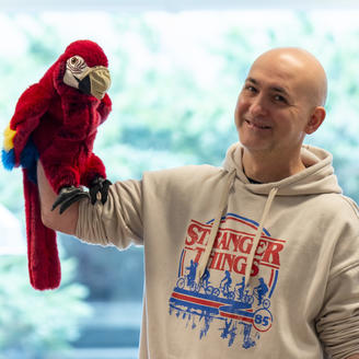 Homme chauve qui tient une marionnette de perroquet