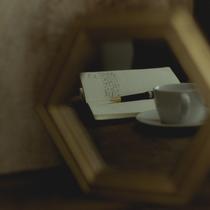 Reflet dans un miroir d'une cahier, d'un stylo et d'une tasse à café.