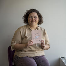 Jeune femme souriante tenant le livre La pluie des autres, de Daphné B.