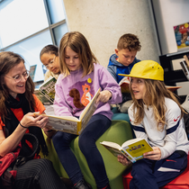 Jeune femme et enfants en train de lire.