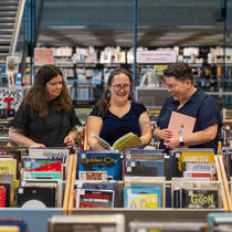 Trois femmes entourées de bacs remplis de bandes dessinées.