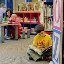 Photographie d'enfants consultant des livres à l'Espace Jeunes de la Grande Bibliothèque de Montréal