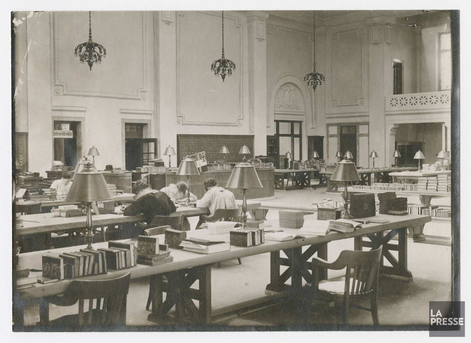 Salle de lecture de la bibliothèque Saint-Sulpice. On aperçoit des membres du personnel, assis à une table, travaillant.