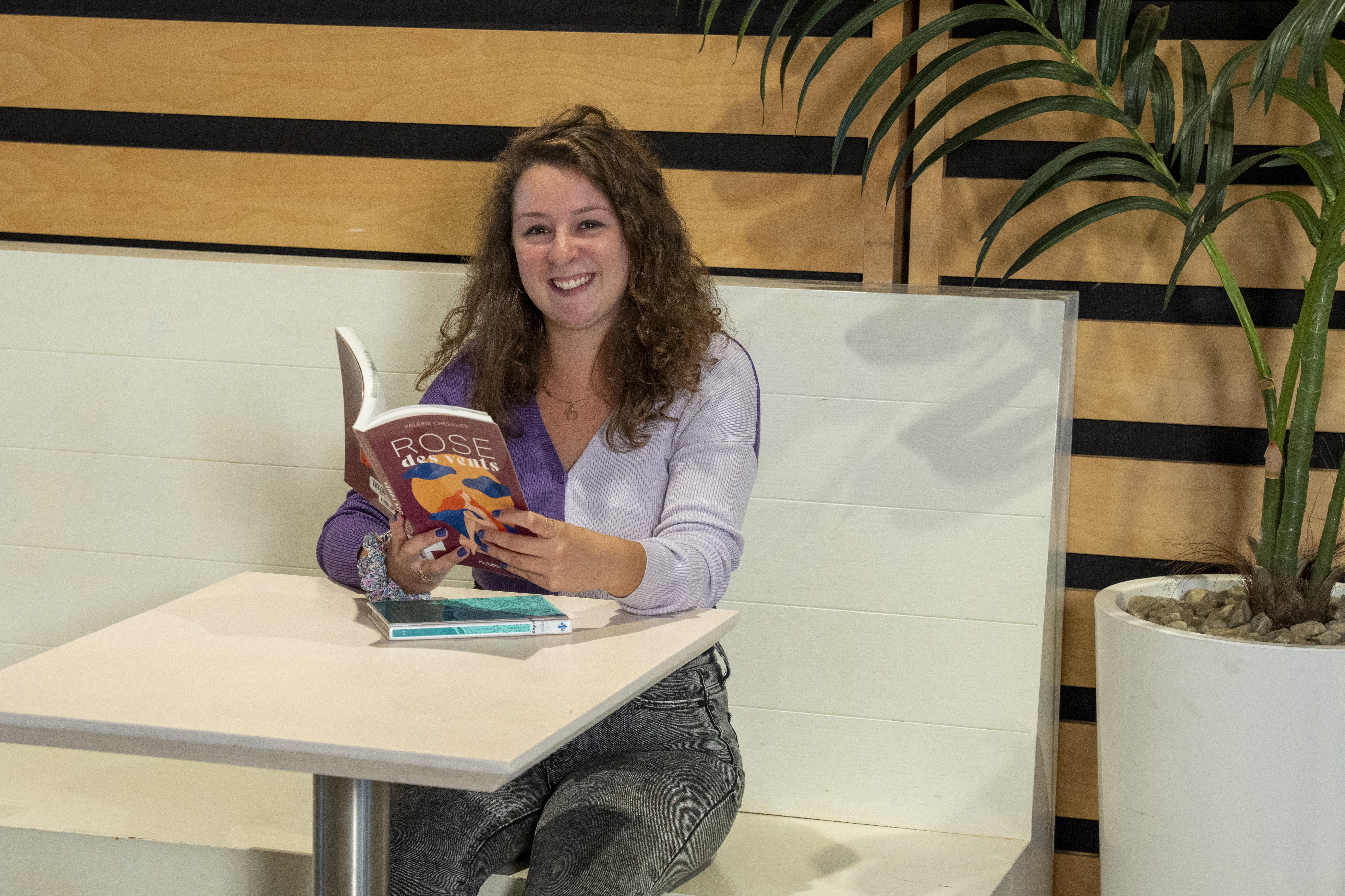 Une femme attablée lit Rose des vents, de Valérie Chevalier.