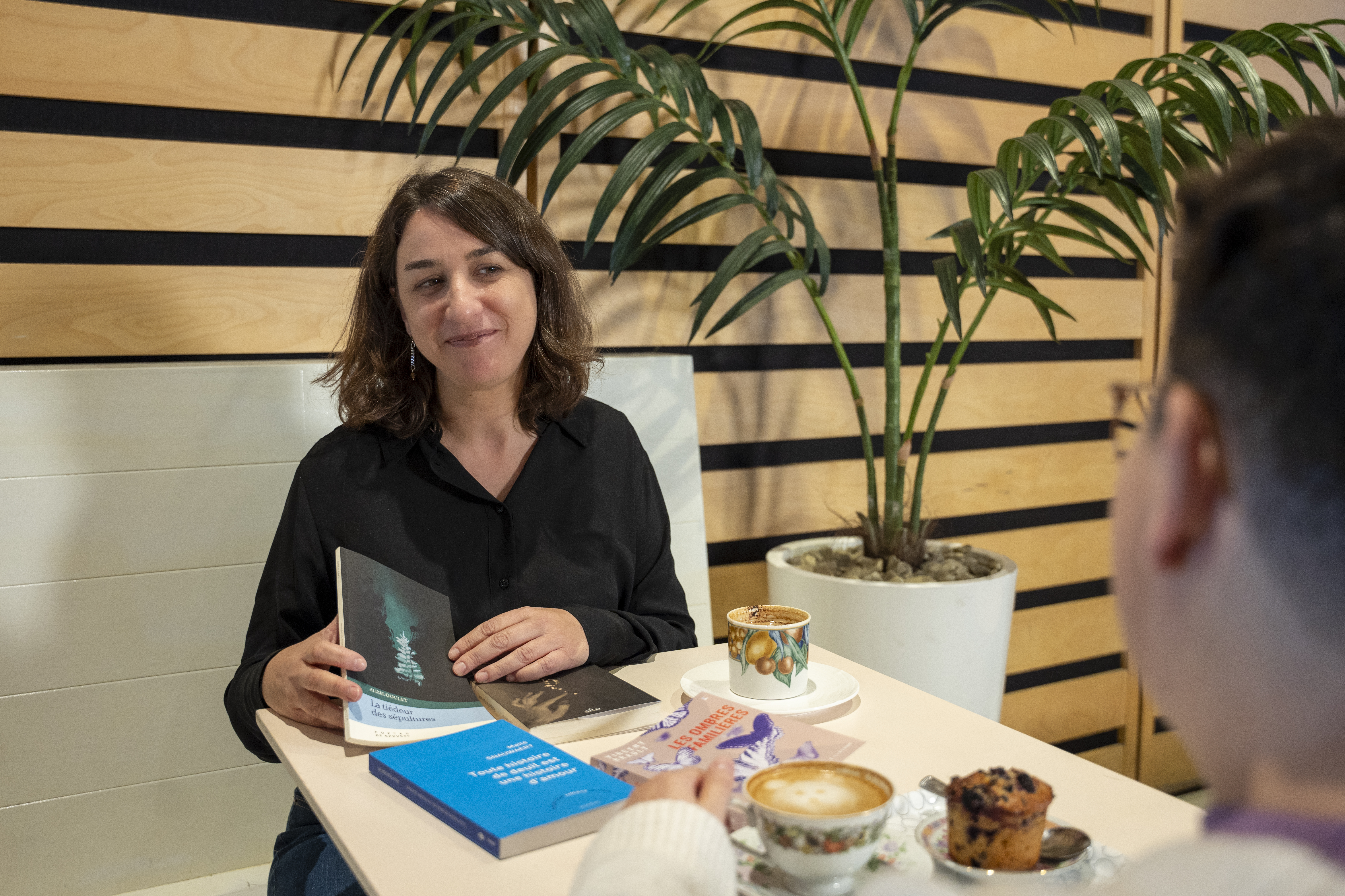 Deux femmes sont attablées devant des cafés, un muffin et des livres.