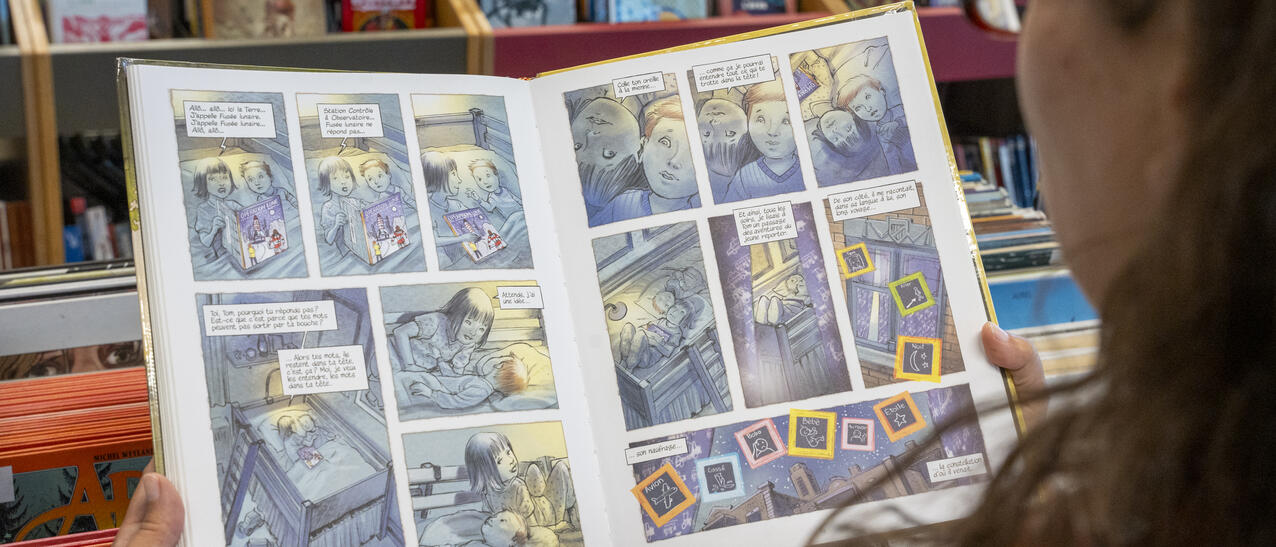 Sur une page du livre Le petit astronaute, de Jean-Paul Eid, deux enfants lisent ensemble un livre de Tintin.