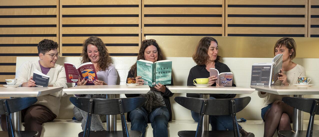 Cinq femmes lisent des livres côte-à-côte.